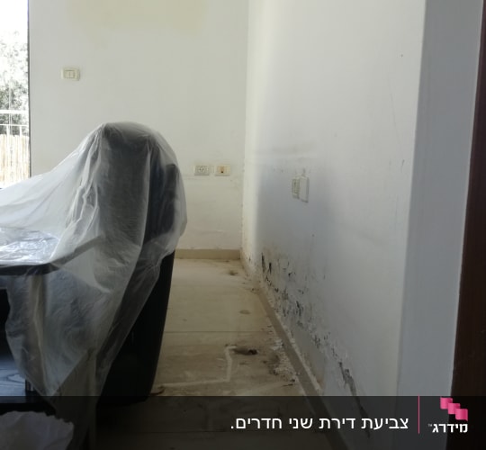 קיר עם סימני רטיבות וציוד מכוסה בניילון